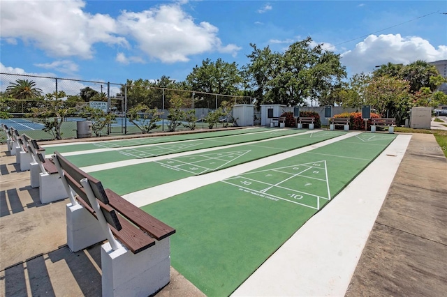 view of home's community with fence, a tennis court, and shuffleboard