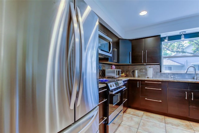 3406 Hollyhock Way, Tampa, FL 33618 - kitchen featuring appliances with stainless steel finishes, a sink, dark brown cabinetry, light tile patterned floors, and tasteful backsplash