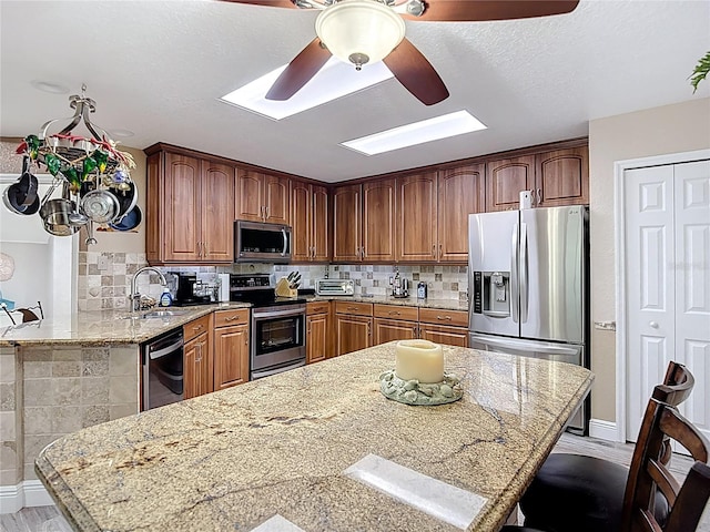 1628 Lullwater Ln, Lutz, FL 33549 - kitchen featuring appliances with stainless steel finishes, a skylight, a sink, a ceiling fan, and tasteful backsplash
