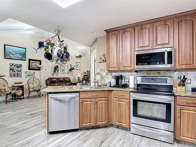 1628 Lullwater Ln, Lutz, FL 33549 - kitchen featuring appliances with stainless steel finishes, a sink, a peninsula, backsplash, and light wood-style floors