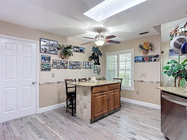 1628 Lullwater Ln, Lutz, FL 33549 - kitchen with dishwasher, brown cabinets, a skylight, baseboards, and a textured ceiling