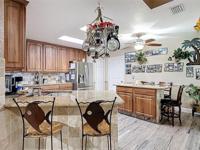 1628 Lullwater Ln, Lutz, FL 33549 - kitchen featuring stainless steel fridge, a peninsula, a kitchen bar, a sink, and light stone counters