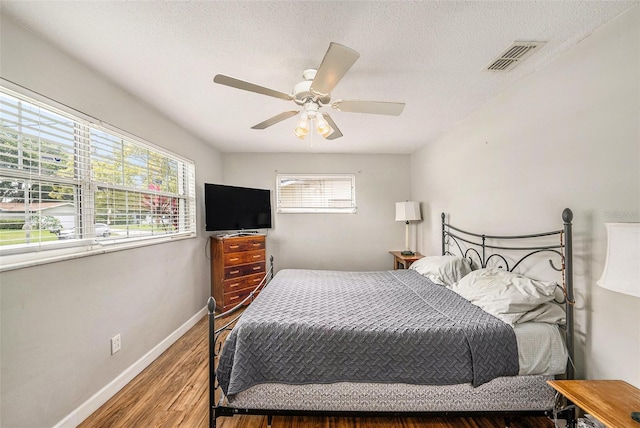 bedroom featuring wood finished floors, baseboards, a textured ceiling, and a ceiling fan