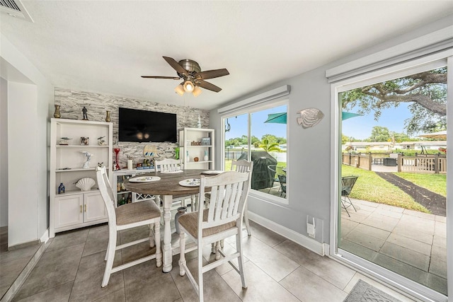 dining room with a ceiling fan, baseboards, and tile patterned floors