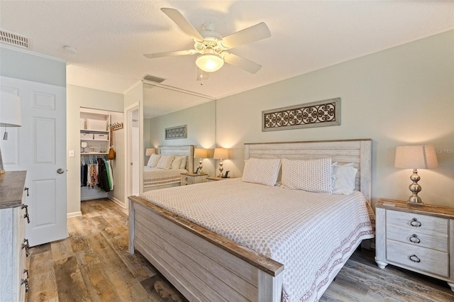 bedroom with wood finished floors, a closet, ceiling fan, and baseboards