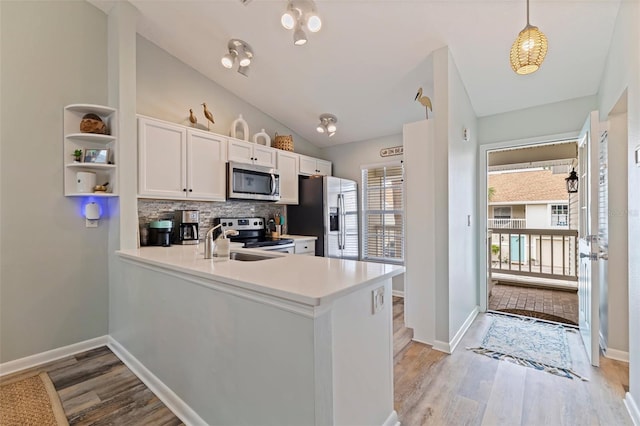 kitchen featuring stainless steel appliances, backsplash, light wood-style floors, lofted ceiling, and white cabinetry