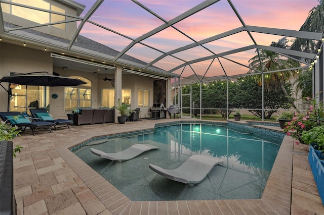 pool at dusk with an outdoor hangout area, a patio area, grilling area, and a ceiling fan