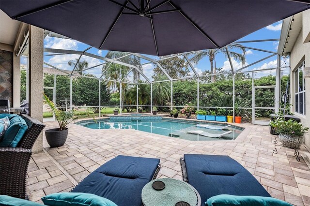 view of swimming pool with a patio area, a pool with connected hot tub, and glass enclosure