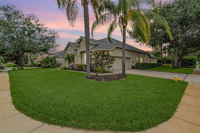 view of front facade featuring a front lawn, stucco siding, concrete driveway, and an attached garage