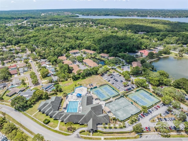 aerial overview of property's location featuring a nearby body of water, a forest, and a pool