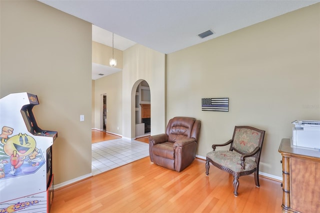 sitting room featuring arched walkways, wood finished floors, and baseboards