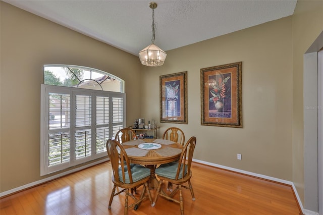 dining area with a chandelier, light wood finished floors, plenty of natural light, baseboards, and a textured ceiling