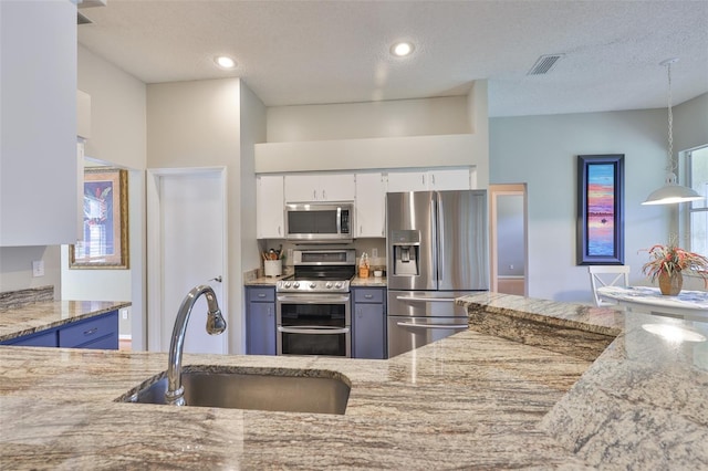 kitchen featuring stainless steel appliances, a sink, light stone countertops, white cabinetry, and recessed lighting