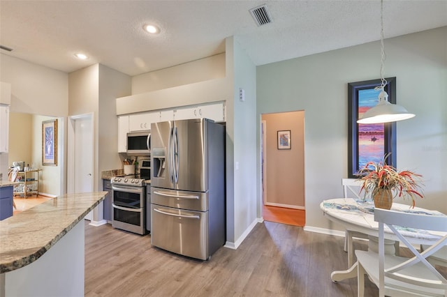 kitchen featuring stainless steel appliances, white cabinets, light wood-style flooring, light stone counters, and baseboards