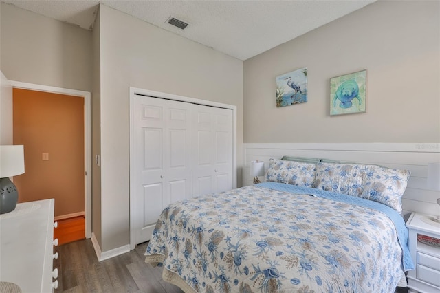 bedroom with wood finished floors, a closet, and baseboards