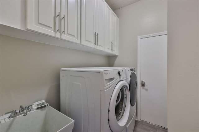 clothes washing area featuring cabinet space, washer and clothes dryer, and wood finished floors