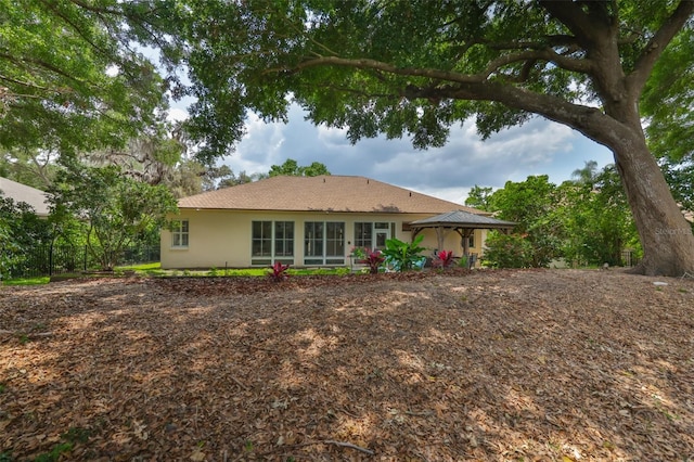 back of property with a gazebo and stucco siding