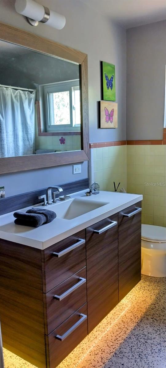 307 Druid Hills Rd, Temple Terrace, FL 33617 - full bathroom featuring tile walls, vanity, toilet, wainscoting, and a shower with shower curtain