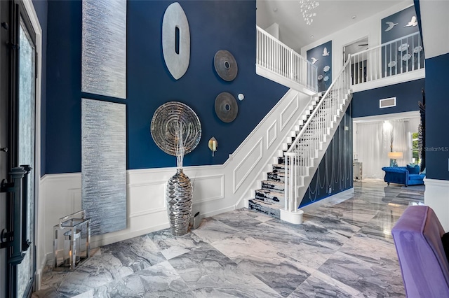19620 Eagle Crest Dr, Lutz, FL 33549 - entryway featuring stairs, a towering ceiling, marble tiled flooring, wainscoting, and a decorative wall