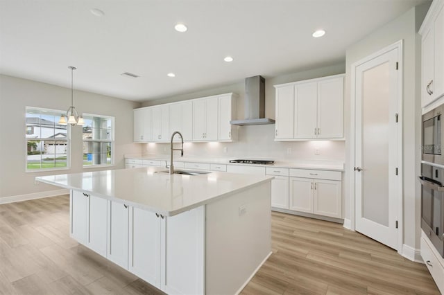 13137 Wellspring Dr, Lithia, FL 33547 - kitchen featuring wall chimney exhaust hood, stainless steel appliances, light countertops, light wood-style floors, and recessed lighting