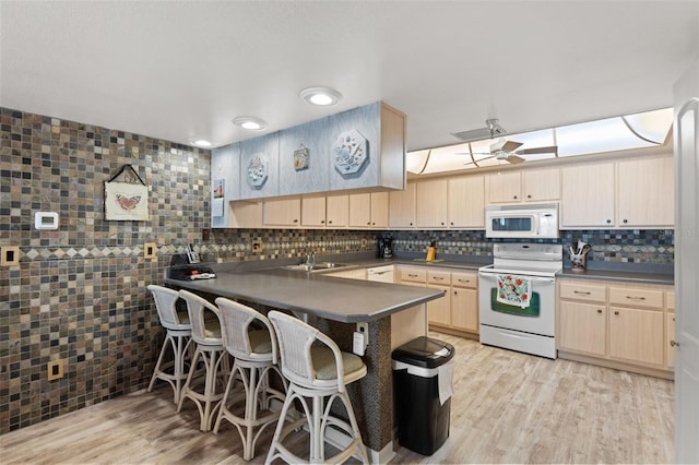 13440 Gulf Blvd Unit 501, Madeira Beach, FL 33708 - kitchen featuring white appliances, a sink, a peninsula, light brown cabinets, and a kitchen breakfast bar