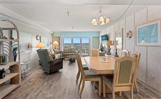 13440 Gulf Blvd Unit 501, Madeira Beach, FL 33708 - dining space featuring wood finished floors, a textured ceiling, a chandelier, and baseboards