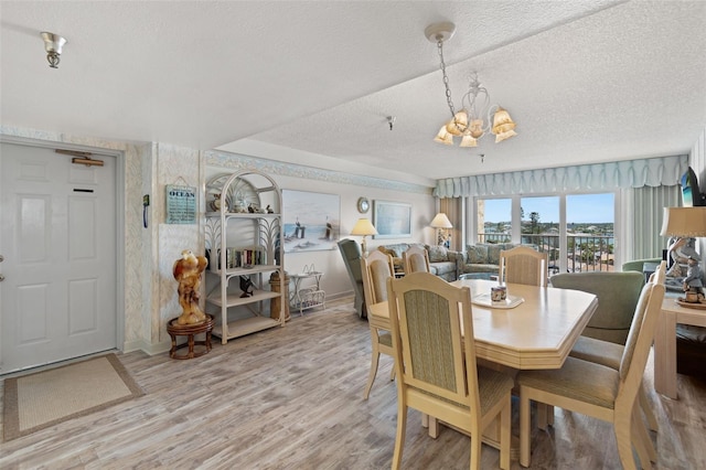 13440 Gulf Blvd Unit 501, Madeira Beach, FL 33708 - dining space with a chandelier, a textured ceiling, wood finished floors, and baseboards