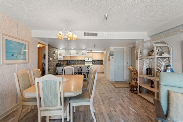 13440 Gulf Blvd Unit 501, Madeira Beach, FL 33708 - dining area with a chandelier, light wood-style floors, and a textured ceiling