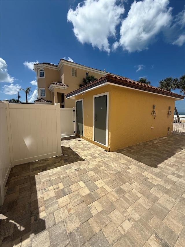 13440 Gulf Blvd Unit 501, Madeira Beach, FL 33708 - rear view of house featuring stucco siding, a patio, a tile roof, and a gate