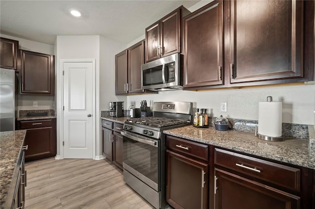 9640 Lemon Drop Loop, Ruskin, FL 33573 - kitchen with appliances with stainless steel finishes, light wood-type flooring, dark brown cabinetry, dark stone countertops, and recessed lighting