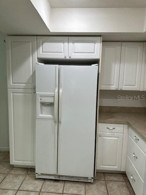 kitchen featuring white fridge with ice dispenser, white cabinets, and light tile patterned floors