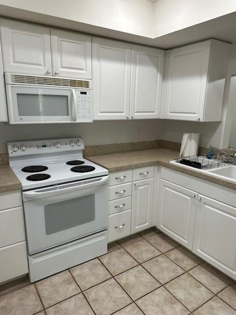 kitchen with white appliances, white cabinetry, light tile patterned floors, and light countertops