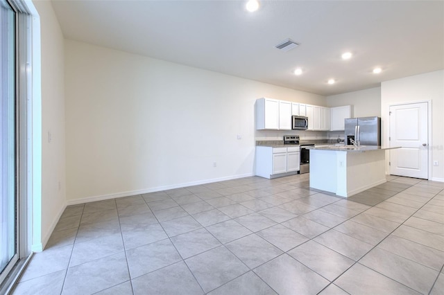 2882 Peony Prairie Ln, Wesley Chapel, FL 33543 - kitchen with appliances with stainless steel finishes, light tile patterned flooring, recessed lighting, white cabinetry, and an island with sink