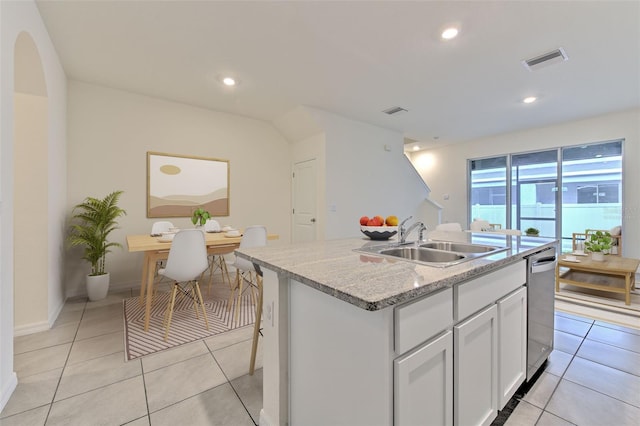 2882 Peony Prairie Ln, Wesley Chapel, FL 33543 - kitchen with white cabinets, an island with sink, light tile patterned flooring, light stone countertops, and dishwasher