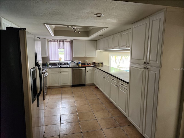 6906 Shady Pl, Tampa, FL 33634 - kitchen featuring appliances with stainless steel finishes, a sink, a textured ceiling, a raised ceiling, and light tile patterned floors