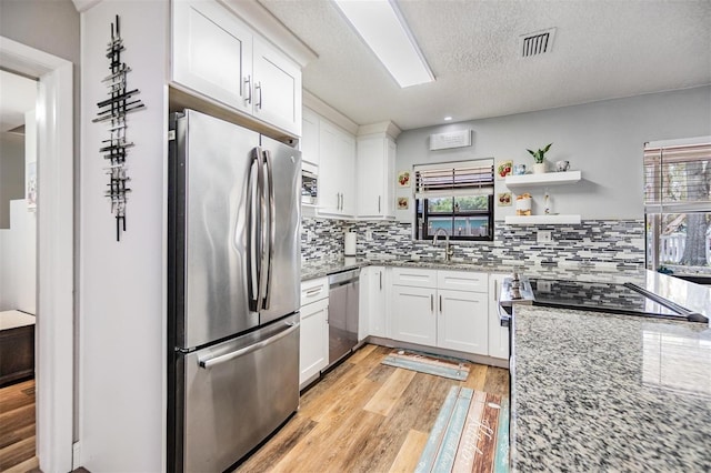 1225 15th St, Palm Harbor, FL 34683 - kitchen with appliances with stainless steel finishes, light wood finished floors, light stone countertops, tasteful backsplash, and a textured ceiling