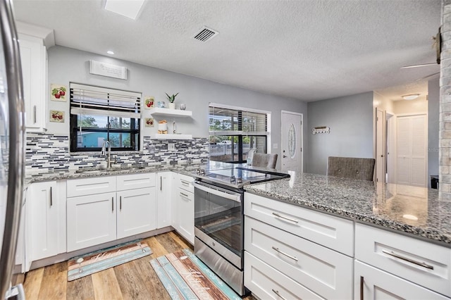 1225 15th St, Palm Harbor, FL 34683 - kitchen featuring stainless steel appliances, a sink, light wood-type flooring, decorative backsplash, and white cabinetry