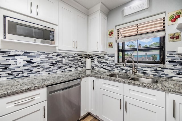 1225 15th St, Palm Harbor, FL 34683 - kitchen with appliances with stainless steel finishes, a sink, tasteful backsplash, white cabinetry, and light stone countertops