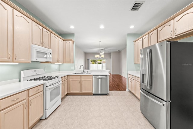 kitchen with appliances with stainless steel finishes, light brown cabinetry, a peninsula, a sink, and recessed lighting