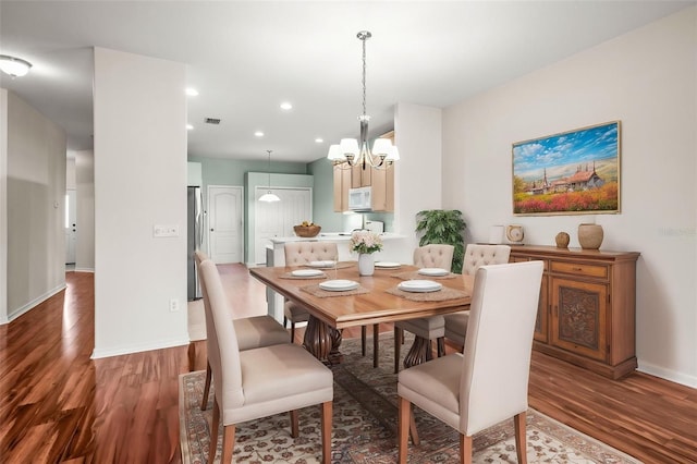 dining room with wood finished floors, a chandelier, baseboards, and recessed lighting
