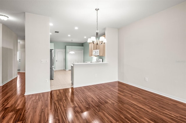 unfurnished living room with a chandelier, wood finished floors, baseboards, and recessed lighting
