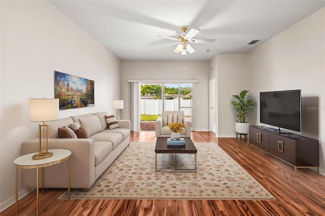 living room featuring wood finished floors, baseboards, and a ceiling fan