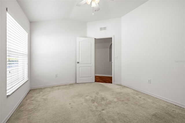 empty room with carpet floors, ceiling fan, baseboards, and lofted ceiling