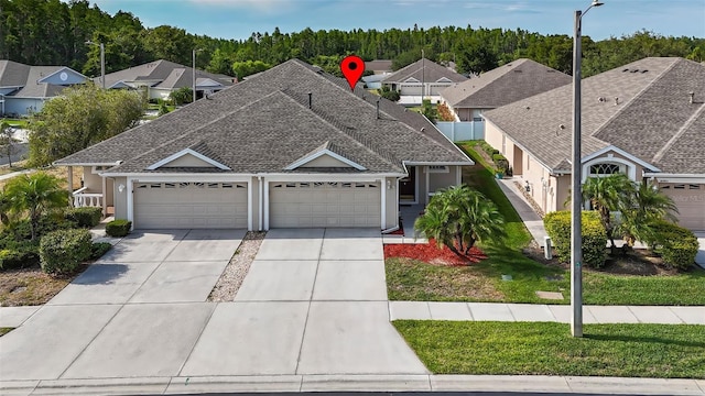 view of front of home with concrete driveway, a garage, roof with shingles, and a residential view