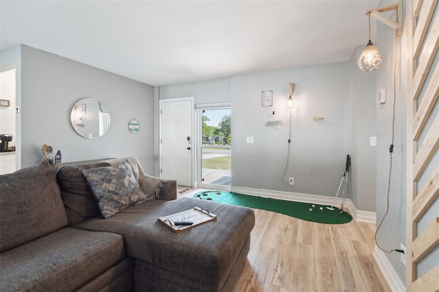 living room with light wood-type flooring, baseboards, and stairway