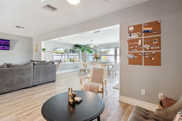 living area featuring ceiling fan, baseboards, and light wood-style floors
