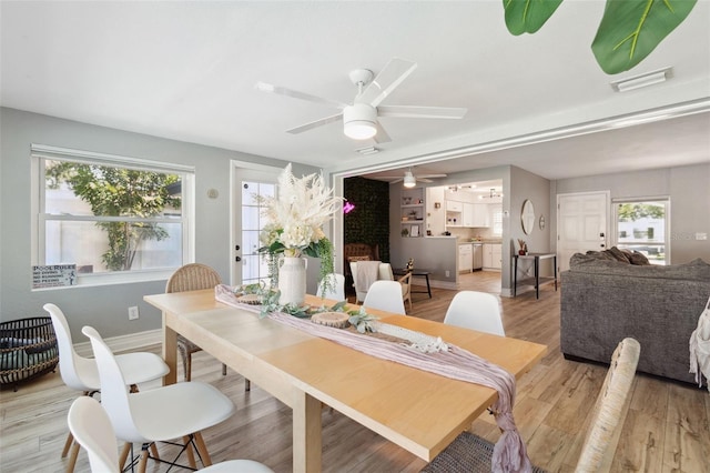 dining space featuring a ceiling fan, light wood-type flooring, and baseboards