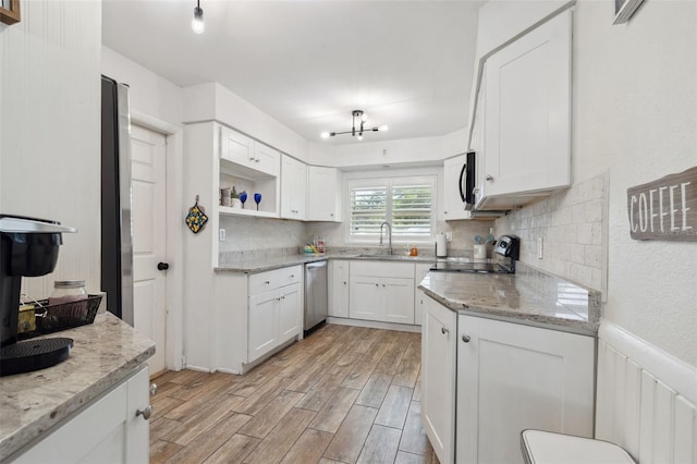 kitchen with appliances with stainless steel finishes, light wood finished floors, white cabinets, and tasteful backsplash