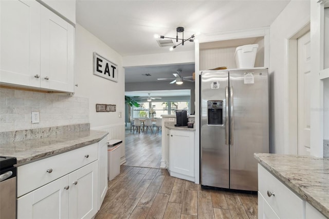kitchen with stainless steel fridge, a chandelier, light wood finished floors, open shelves, and decorative backsplash