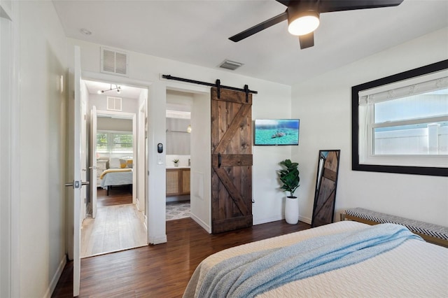 bedroom featuring a barn door, dark wood finished floors, baseboards, and a ceiling fan